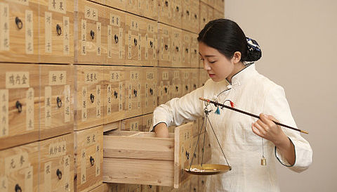 Chinesische Apothekerin beim Zusammenstellung einer Rezeptur